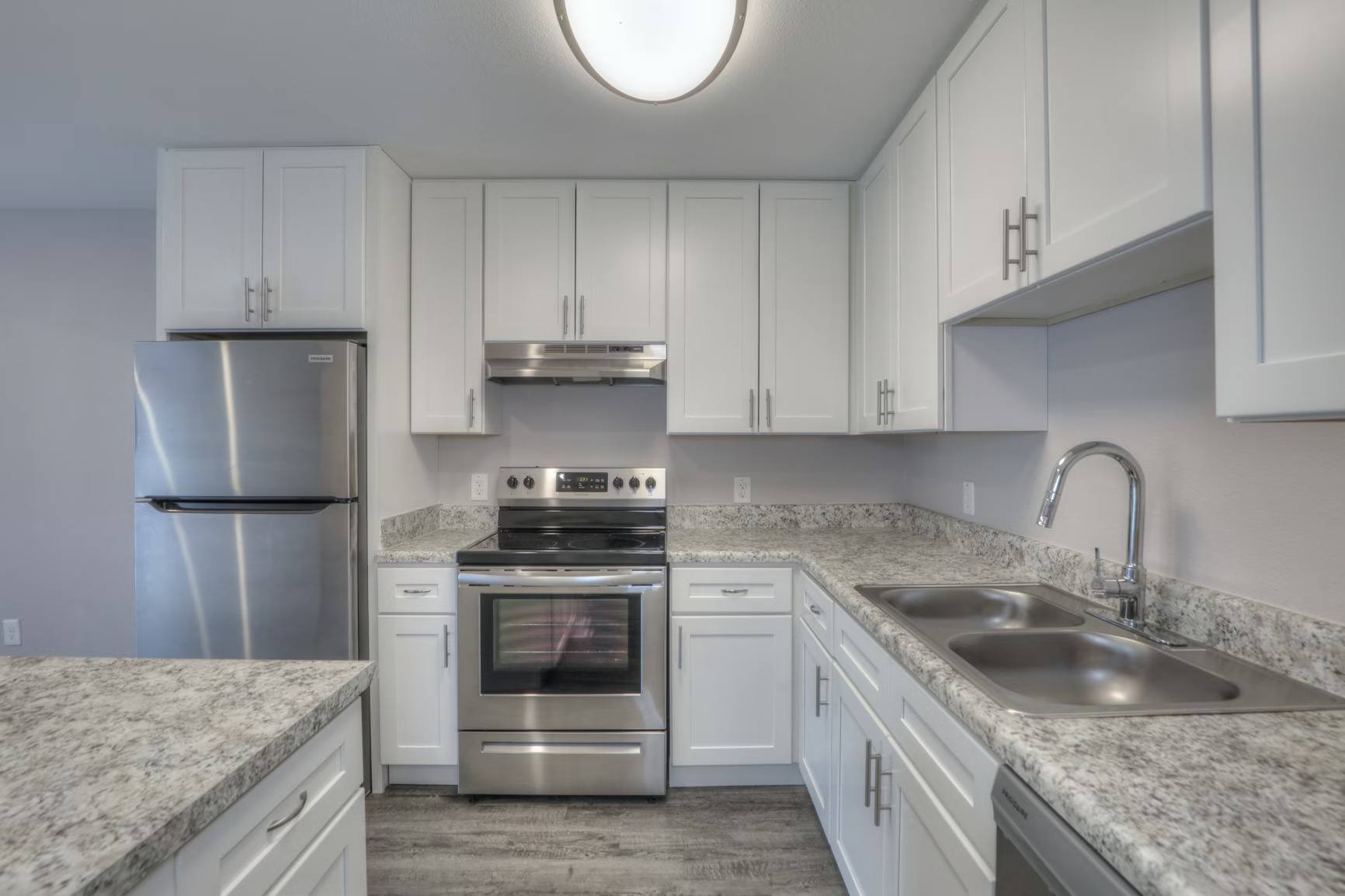 A kitchen with white cabinets and granite countertops.